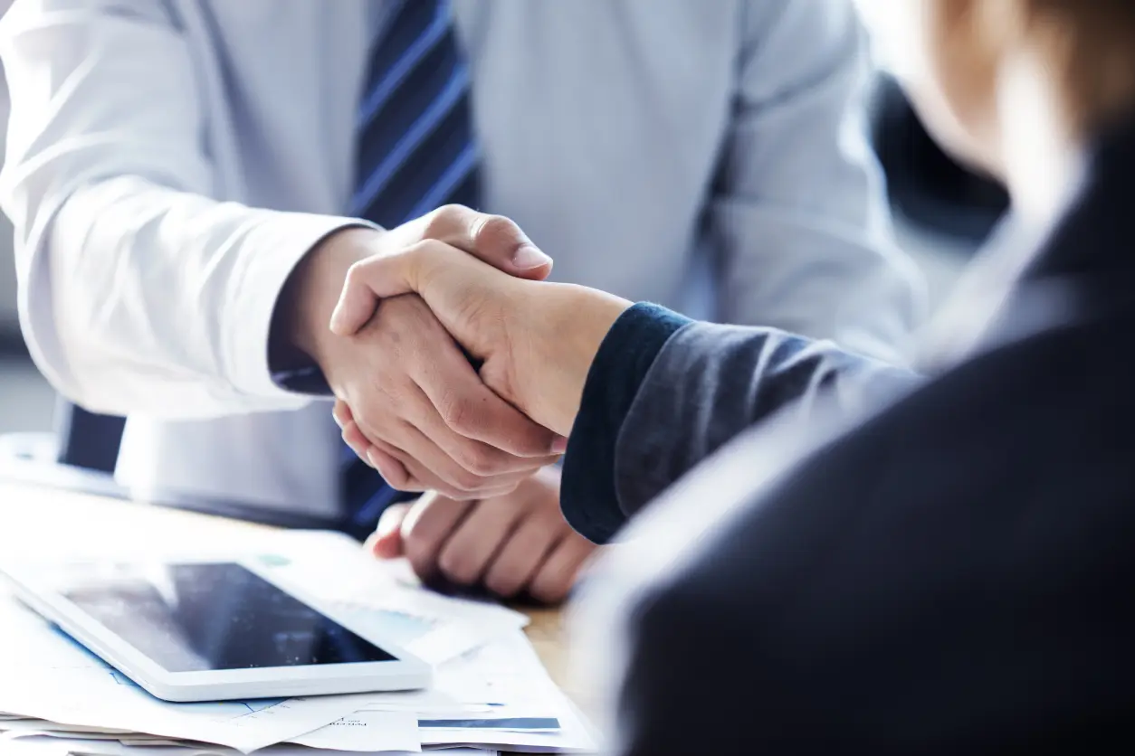 Business handshake over a desk with tablet.