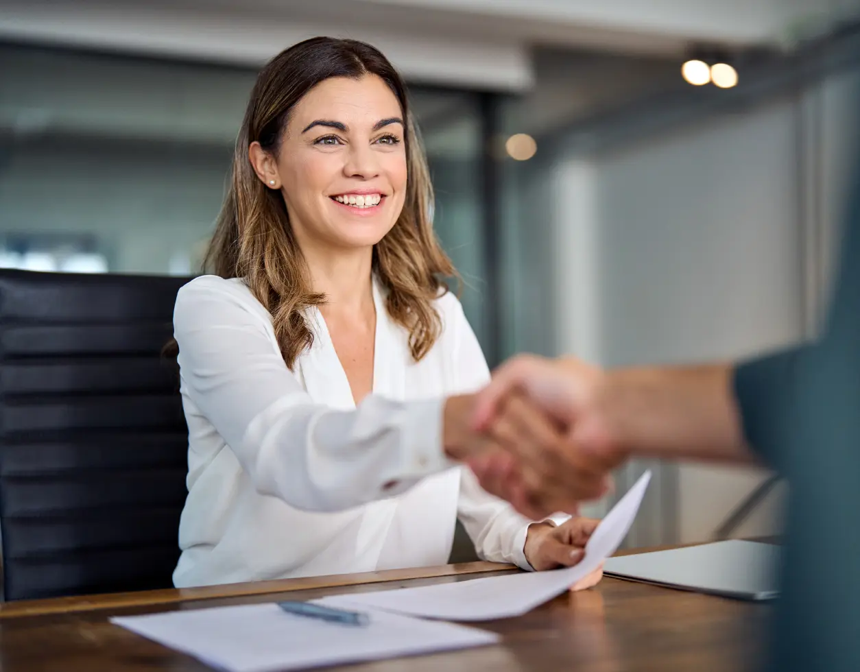 Smiling woman in office, shaking hands.