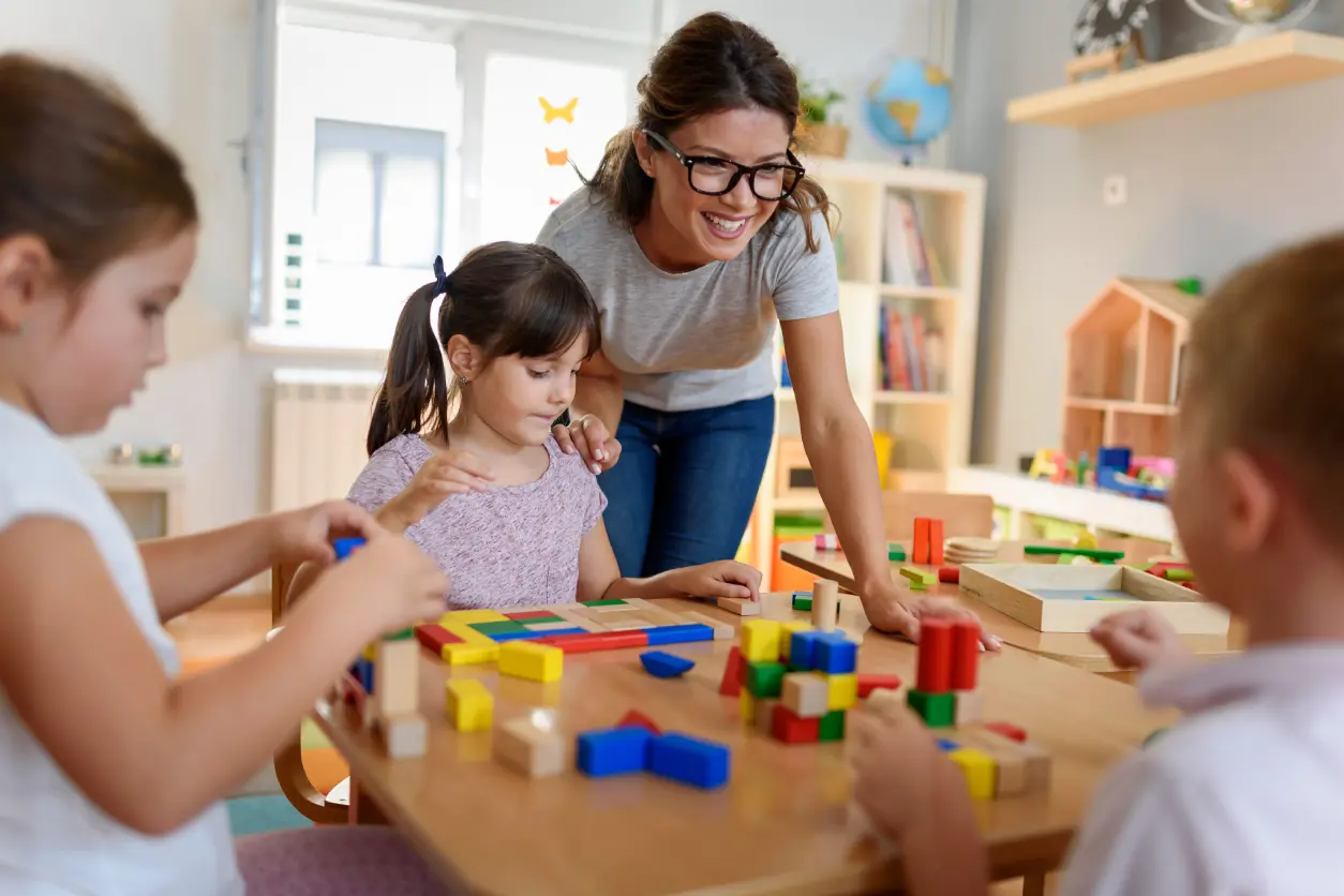 Children and teacher playing with building blocks.