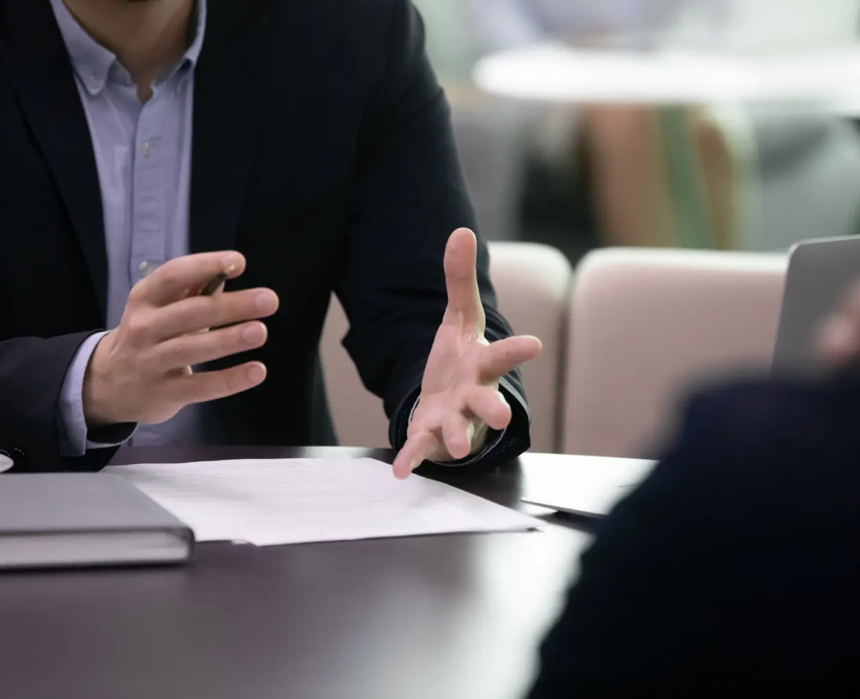 Business meeting with hand gestures, discussing documents.