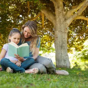 Woman and girl reading under large tree
